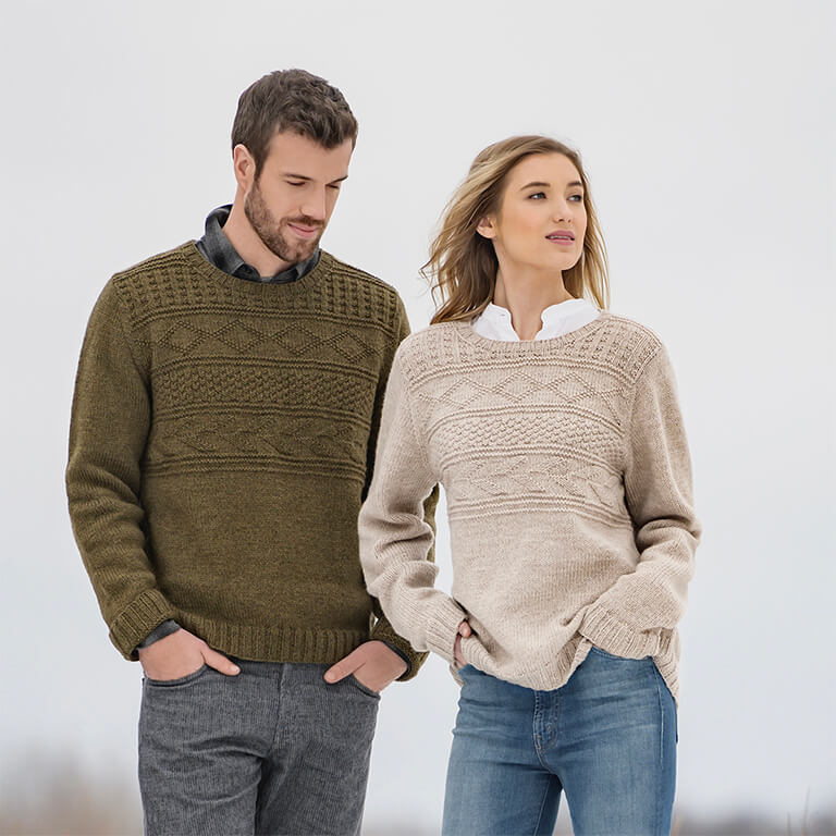 male model on left in pemberton pullover in mossy green color of woolstok, female model on right in pemberton pullover in color drift wood in woolstok